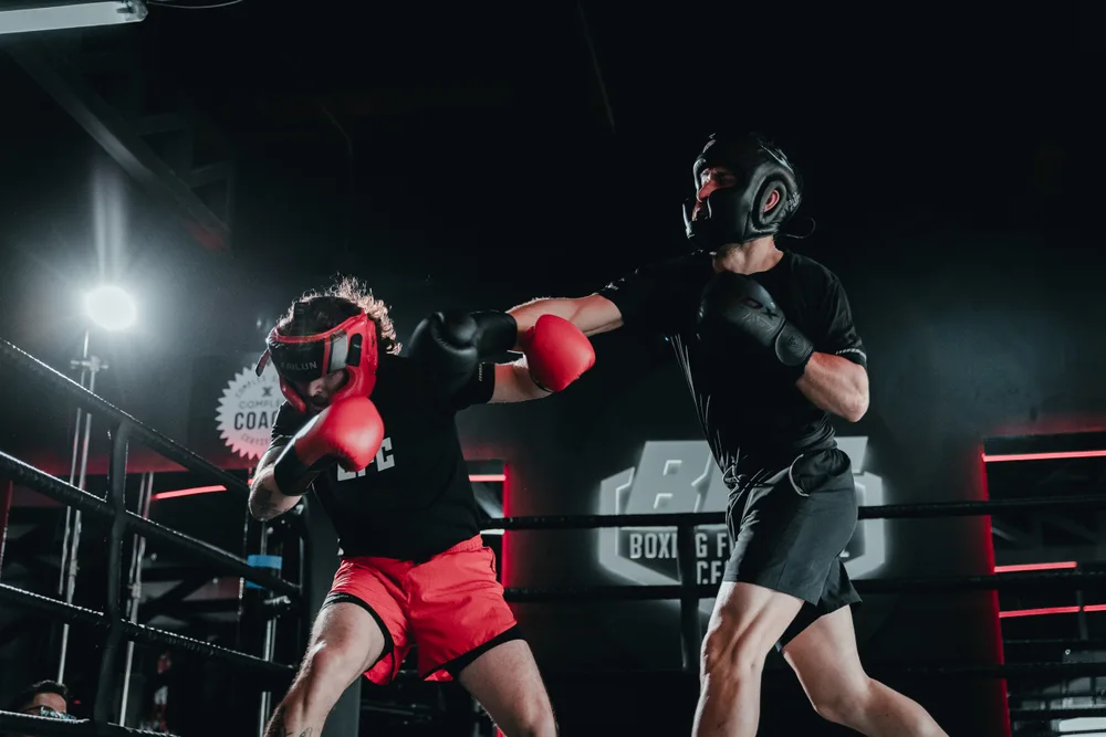 Boxeador con guantes rojos conecta un golpe durante un sparring con casco